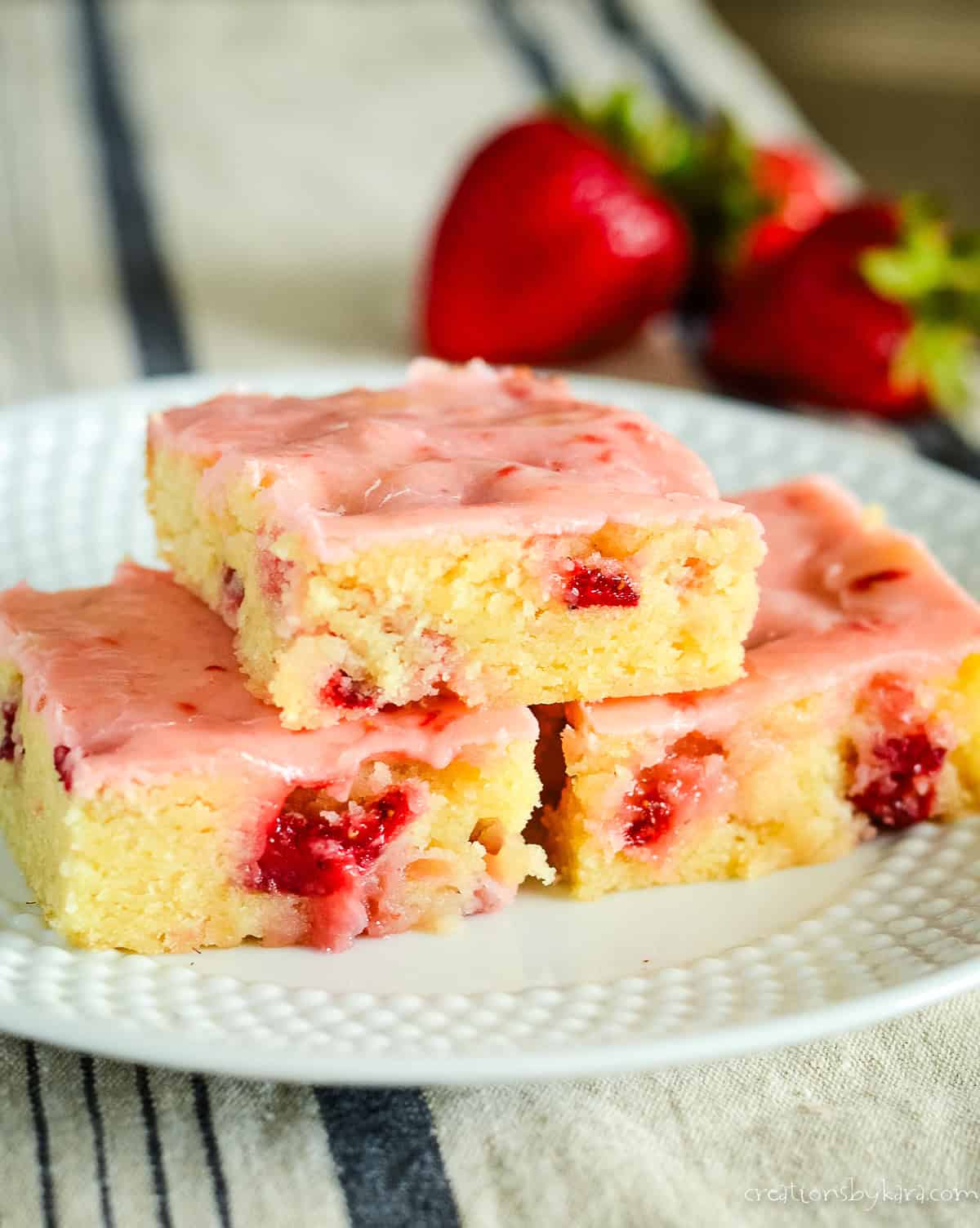 strawberry lemon blondies on a plate with berries in the background