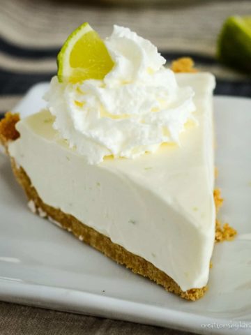 slice of no bake key lime pie with whipped cream and a slice of lime