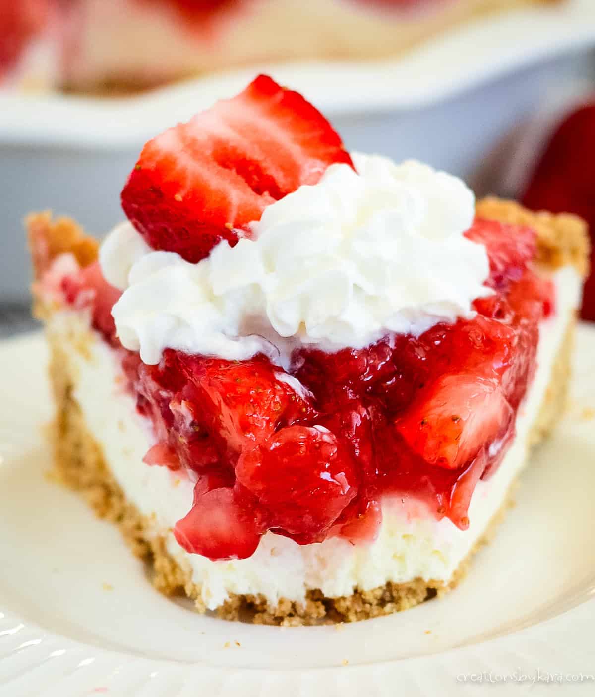 slice of strawberry cream pie on a plate with a bite taken out of it.