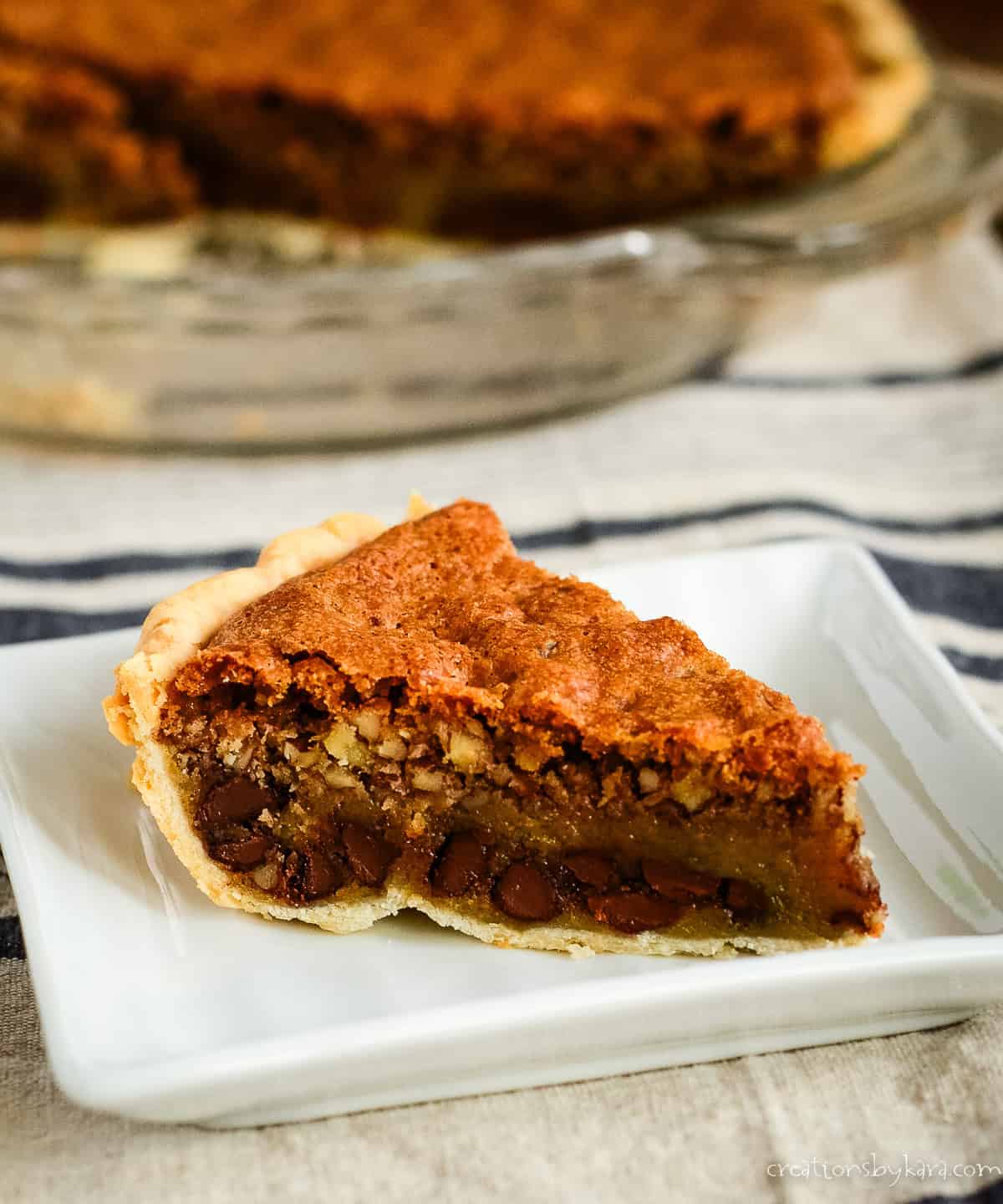 slice of chocolate chip pie with pecans on a white plate